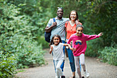 Happy family running and hiking on trail in woods