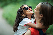 Happy mother holding daughter in sunglasses