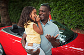 Happy father holding daughter by convertible
