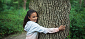 Serene girl hugging tree trunk in woods
