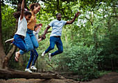 Carefree family jumping off fallen log in woods