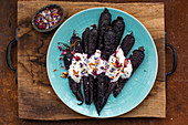 Roasted purple carrots with a yogurt dressing topped with seasal
