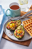 Baked avocado with ham and egg, served with homemade waffle