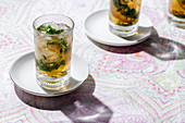 Glasses of cold refreshing tea with ice cubes and lemon slices placed on table