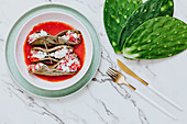 Roasted cactus leaves with tasty mix in tomato sauce, golden cutlery and fresh ingredient