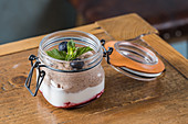 Chocolate mousse garnished with blueberries and sprig of mint and placed on wooden table in cafe