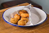 Potato croquettes on plate placed on wooden table in cafeteria