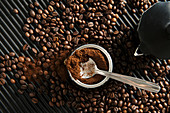 Gemahlener Kaffee in Espressokanne und verstreute Kaffeebohnen