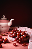 Still life composition with white porcelain teapot and tea spoon placed on round table