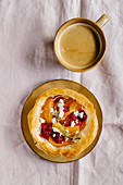 Tarts made of filo dough and filled with sliced fruits served with cup of aromatic coffee with milk
