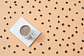 Mug with fresh hot coffee served on white tray on beige surface with scattered coffee beans