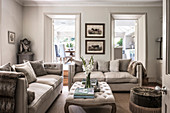 Gladioli and books on buttoned ottoman in split level living room with view to conservatory extension