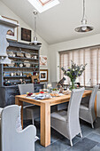 Pendant lights and closed Venetian blinds with wooden table and kitchen dresser