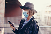 Woman in face mask using smartphone
