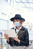 Woman in face mask using digital tablet