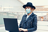 Woman in face mask using laptop