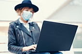 Woman in face mask using laptop