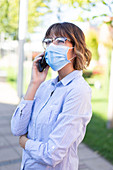 Businesswoman in face mask making phone call