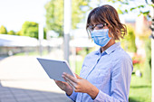 Businesswoman in face mask using digital tablet
