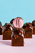Würfelförmige Schokoladenmuffins verziert mit rosa Macaron