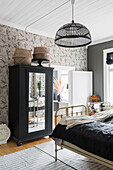 Black wardrobe with mirrored door and old metal twin beds in the guest room