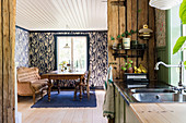 Blick aus der Küche ins Esszimmer mit antikem Holztisch, Sofa und Tapete