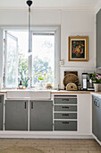 Kitchen with grey cupboard fronts in country-house style; window with garden view