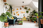 Viele Grünpflanzen, Sofa und Designerleuchte im Wohnzimmer