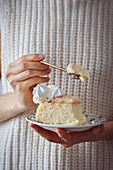 Woman is holding a plate with a piece of cheesecake