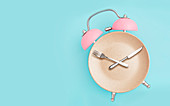 Wecker und Teller mit Besteck - Symbolbild für intermittierendes Fasten (Diät)
