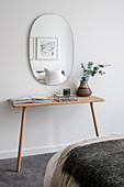 Oval mirror above the console table in a minimalist bedroom