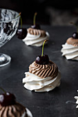 Tasty Pavlova desserts with chocolate cream and ripe cherry placed on table