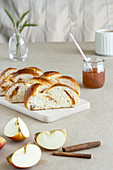 Fresh brioche made from butter dough with jam on wooden board next to glass jar of jam