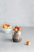 Glass jar with chocolate pudding consisted of yogurt and chia seed and garnished with white cherry