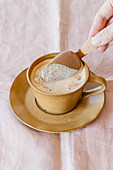 Hand hält Stieleis in eine Tasse Kaffee