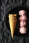 Homemade cherry ice cream scoops arranged on table with waffle cones