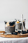 Glass jars with delicious chia puddings made of fresh tasty almond milk and chia seeds with honey topped with blackberries and sliced banana