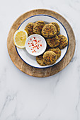 Dish full of lentil falafel served with yogurt sauce on a wooden table