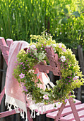 Wreath of lady's mantle, mallows, Queen Anne's lace and gypsophila hung on chair backrest