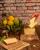 Lemon and poppy seeds cake with missing bite over table with cake and fresh whole lemons