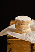 Pile of fresh Polvorones on paper placed on wooden table in studio on black background