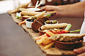 Crop anonymous person holding rustic wooden tray with various types of appetizers during party