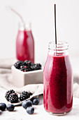 Berries fresh smoothies in glass bottles over a marble surface