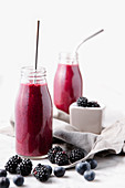 Berries smoothie in glass bottles with reusable metal straws