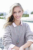 Junge blonde Frau in hellem Pullover am Strand