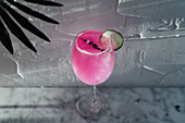 Pinker Cocktail mit Kräutern und Gurkenscheibe