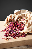 Dried rose petals in and next to a paper bag