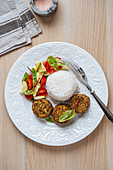 Vegan cutlets served with white rice and fresh vegetable salad on wooden table