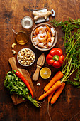 Gemüse, Kräuter, Nüsse, Ingwer, Zitruspresse und gekochte Garnelen auf Holztisch