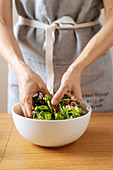 Mixing fresh herbs in bowl for healthy vegan salad